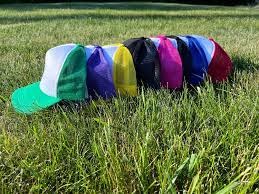 Una hilera de coloridas gorras de camionero de varios colores sobre la hierba.