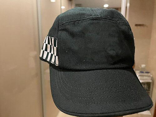 Gorra negra de servicio de policía con un motivo a cuadros en el lateral y un logotipo de placa en la parte delantera, con un emblema rojo y blanco con un diseño de estrella.