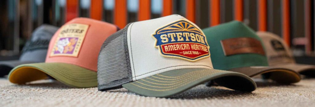 Gorra negra de camionero con parte trasera de malla, con el logotipo "CJM FILM LOGISTICS" en verde y blanco y un gráfico de un camión.