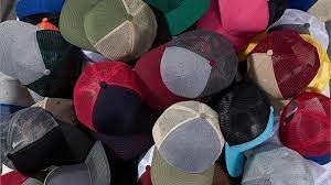 Pila de coloridas gorras de camionero con parte trasera de malla y diversos colores de tejido, vistas desde arriba.