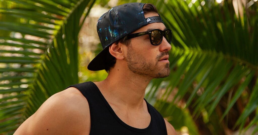Man wearing black backwards baseball cap and sunglasses