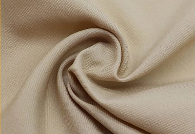 Close-up of beige twill fabric with visible diagonal weave texture.