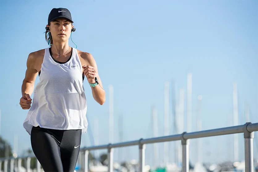 Woman running outdoors in athletic wear.