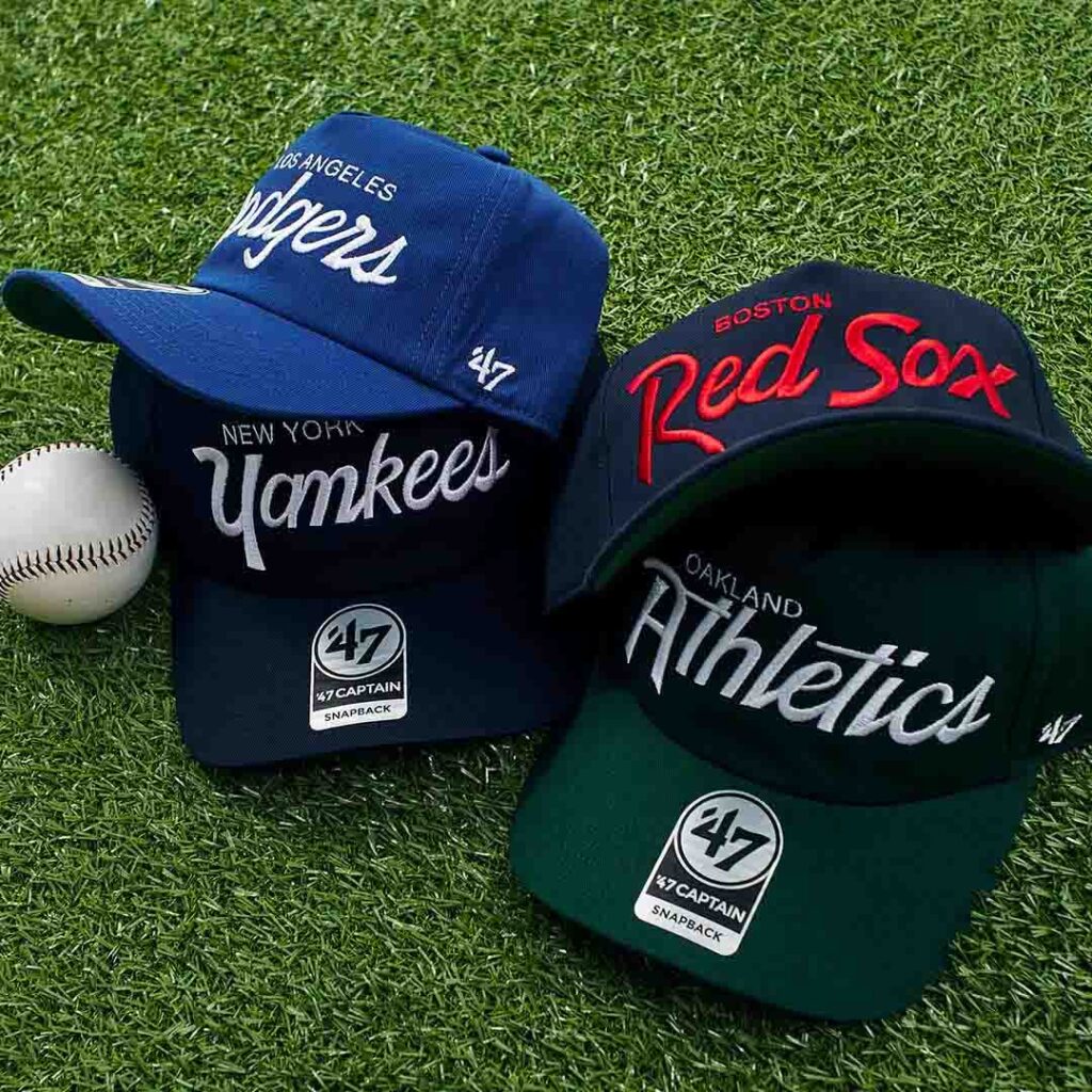 Snapback hats featuring Dodgers, Yankees, Red Sox, and Athletics logos on grass
