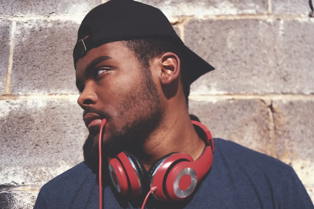 Man wearing red headphones by brick wall