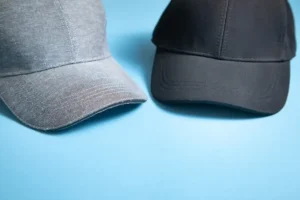Kappen aus grauer Baumwolle und schwarzem Polyester auf blauem Hintergrund