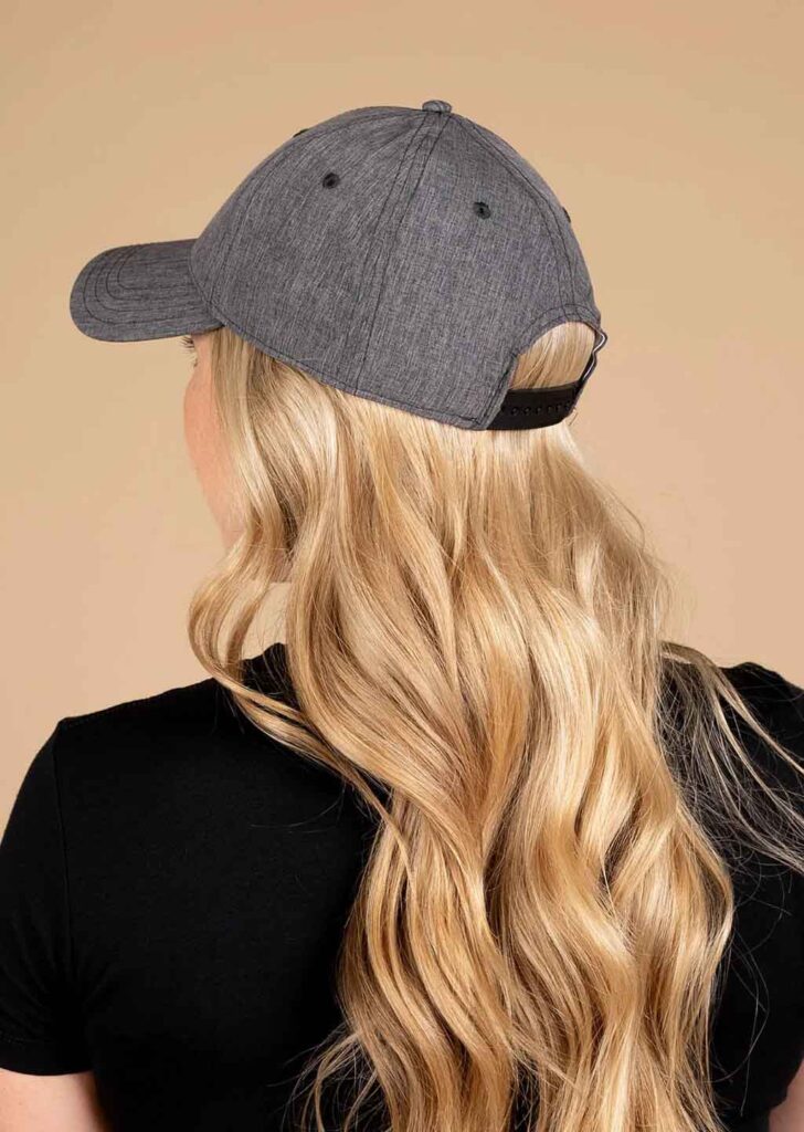 Vista posteriore di una donna con cappellino da baseball grigio e lunghi capelli biondi.