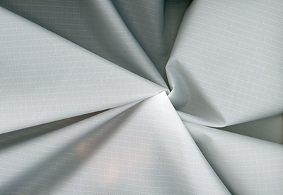 Close-up of light gray ripstop fabric showing grid pattern and folds.