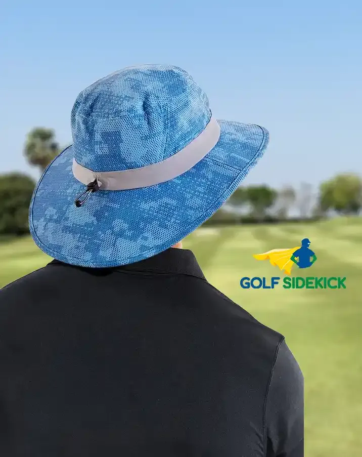 En golfare i blå solhatt med breda brätten och ljust band står på en grönskande golfbana under en klar himmel.