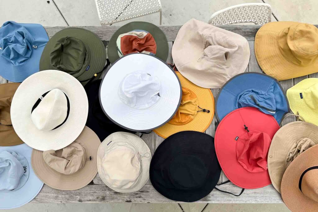 Assorted wide-brim sun hats in various colors displayed on a wooden table.