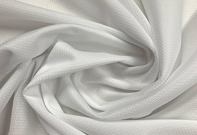 Close-up of white polyester fabric with soft texture and swirling folds.