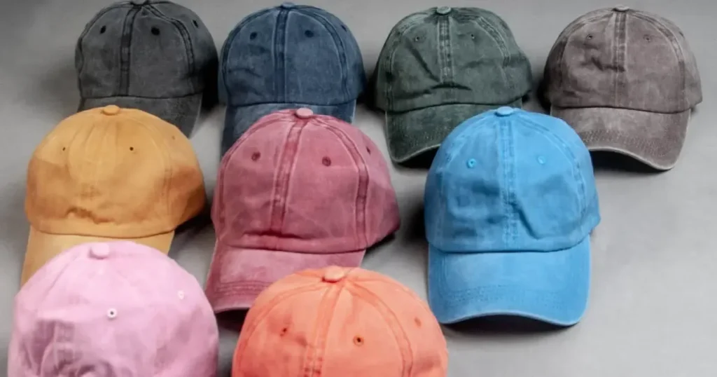 Assorted colorful distressed baseball caps arranged on gray surface.