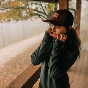 Frau mit kastanienbrauner Mesh-Trucker-Kappe im Freien