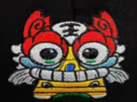 Bright embroidered lion mask with red, blue, yellow, and white details on black background.