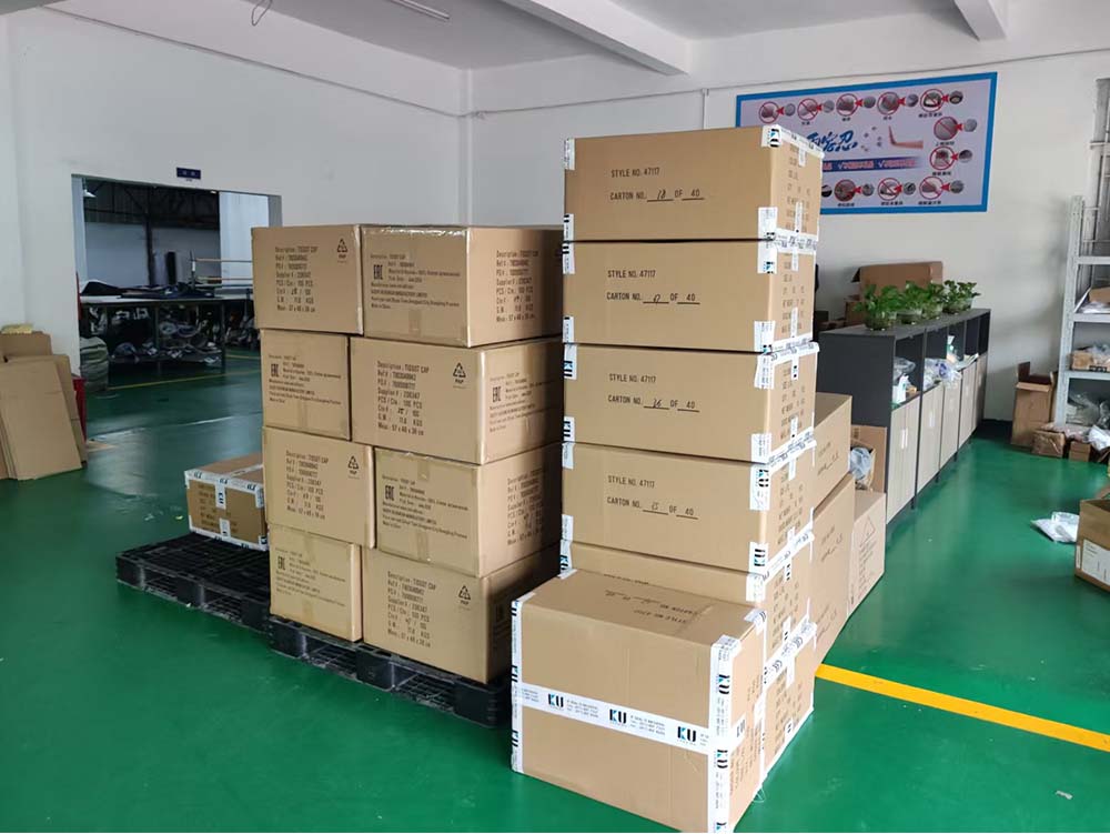Stacks of sealed cardboard boxes arranged on pallets in a warehouse with green flooring.