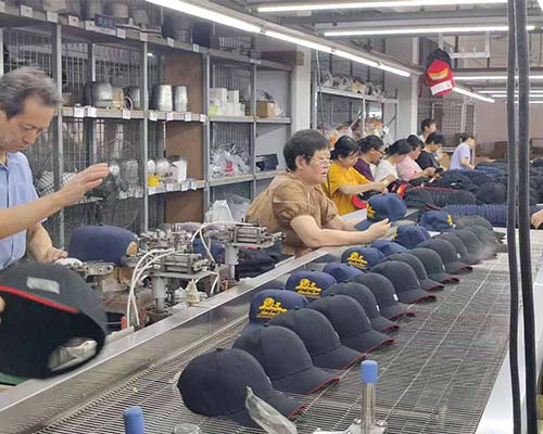 Workers assembling caps on production line.