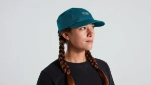 Woman wearing teal blue five-panel cap with braids