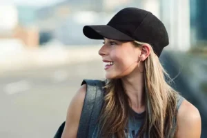 Smiling woman in black baseball cap outdoors