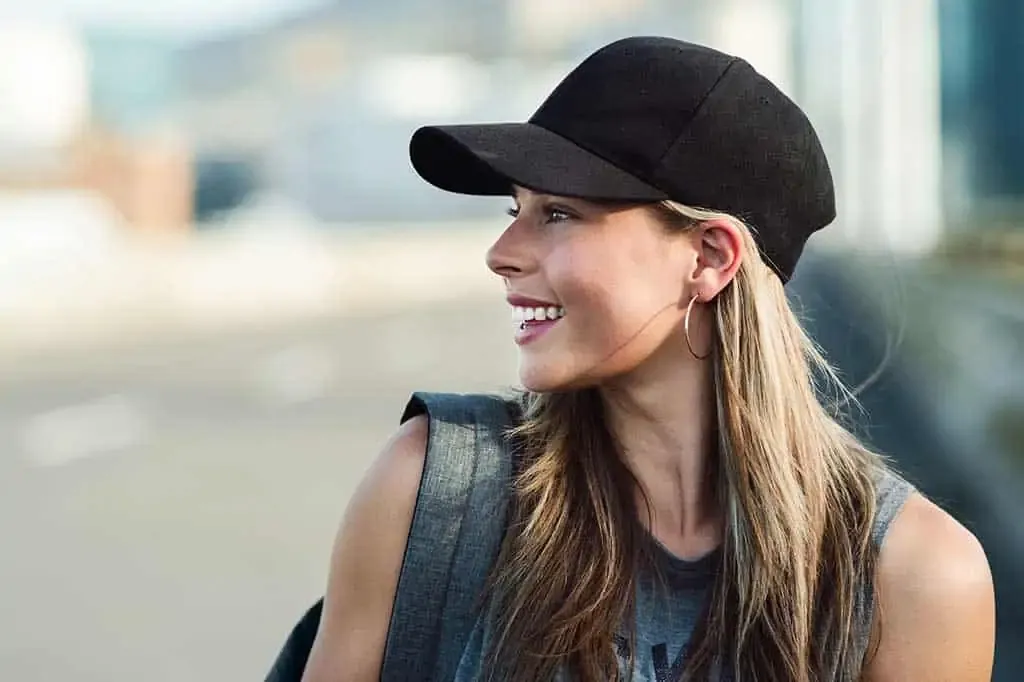 Smiling woman in black baseball cap outdoors