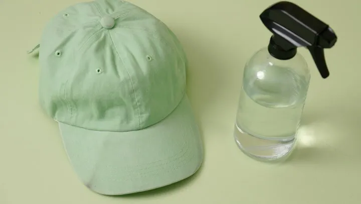 Green baseball cap next to a spray bottle