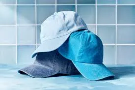 Three blue baseball caps stacked on tiled surface
