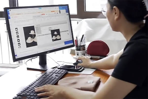 Person working on hat design images on computer monitor.