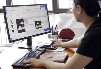 Person working on computer designing hats using software.