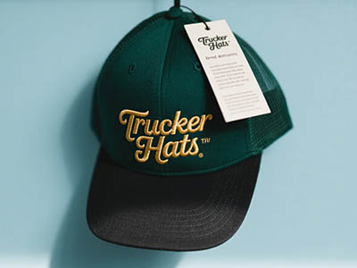 Dark green trucker hat with gold “Trucker Hats” embroidery and a white tag.