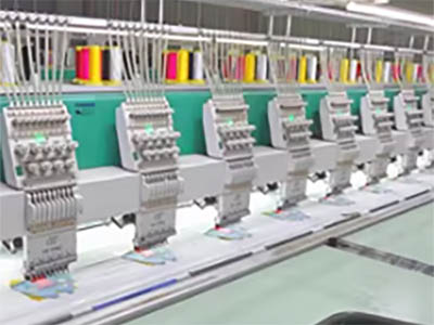 A row of advanced embroidery machines with colorful thread spools in use for cap embroidery production.