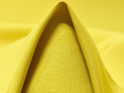 Close-up of smooth yellow fabric folded to form a peak.