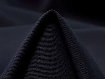 Close-up of folded black fabric with smooth texture and dark background.