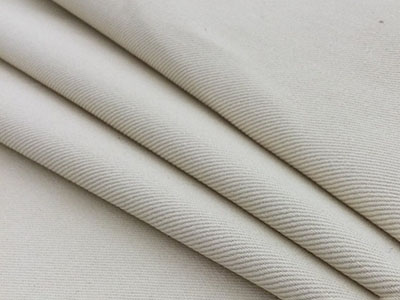 Close-up of beige fabric with fine diagonal weave folded in layers.