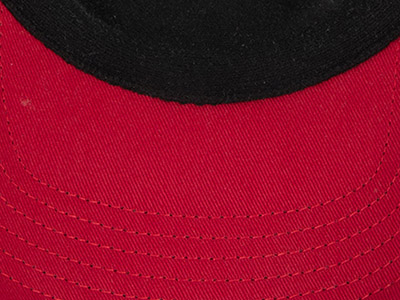 Close-up of a red baseball cap brim with visible stitching detail and black lining.
