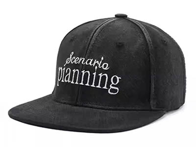 Black flat brim cap with white "scenario planning" embroidery.