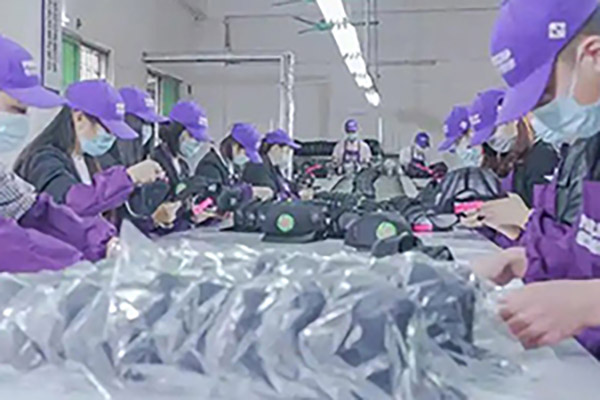 Factory workers in purple uniforms and masks assembling products on line.