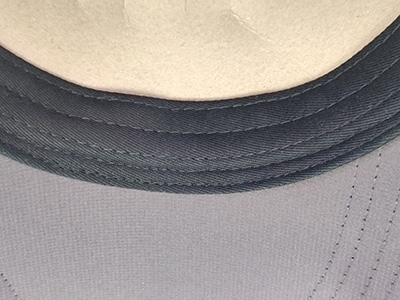 Close-up of black fabric with detailed stitching on hat brim.