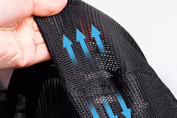Hand stretching black mesh fabric with blue arrows indicating airflow.
