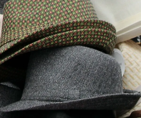 Close-up of folded hats with patterned and gray textured fabric.