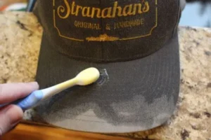 Using toothbrush to clean dirty spot on hat brim