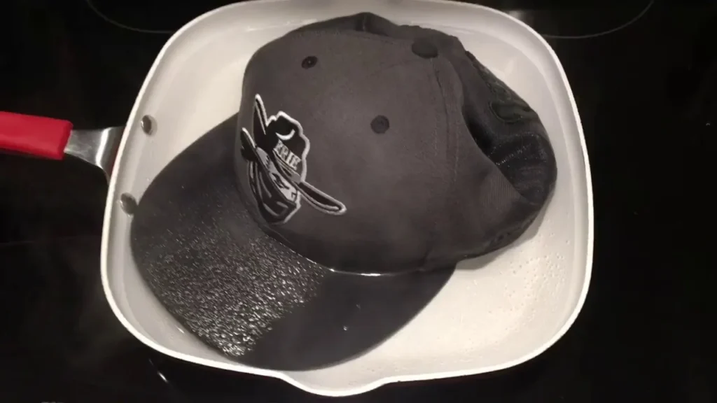 Black cap soaking in water inside white pan on stove.