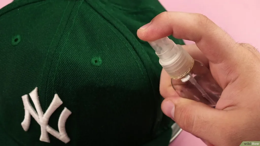 Spraying cleaner on green NY baseball cap