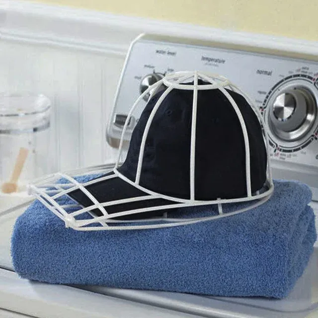 Black cap secured in plastic frame resting on blue towel by washing machine.