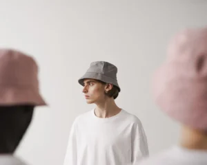 Person wearing gray bucket hat and white shirt looking sideways indoors.