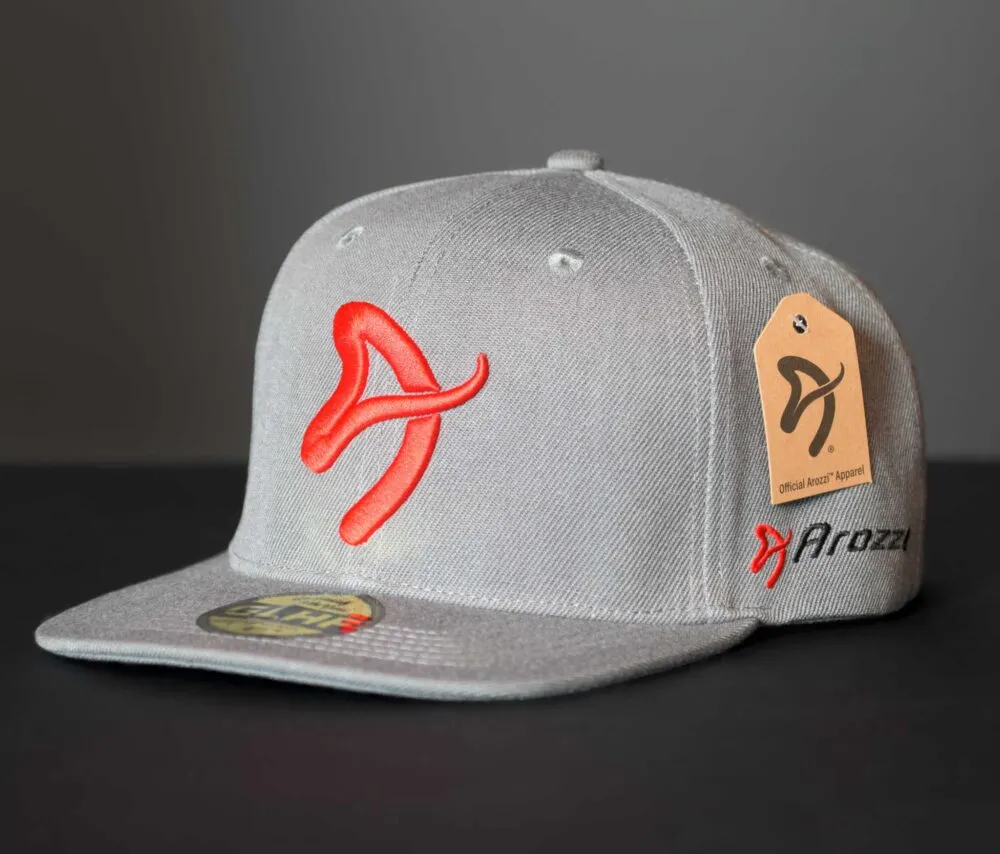Gray snapback hat with red logo and tag on dark background.