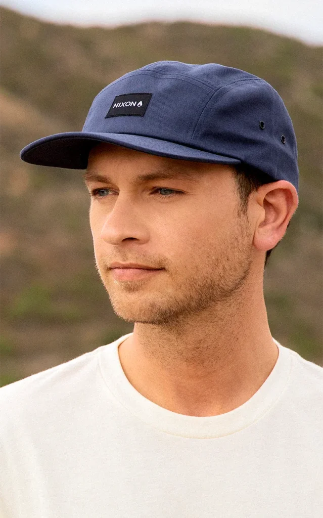 Man wearing navy blue five-panel cap with Nixon logo outdoors