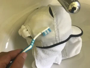 Toothbrush scrubbing white cap under water