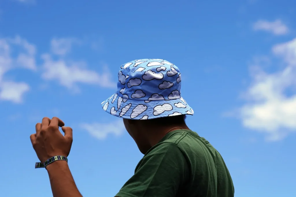 Person wearing blue bucket hat with cloud pattern against clear sky