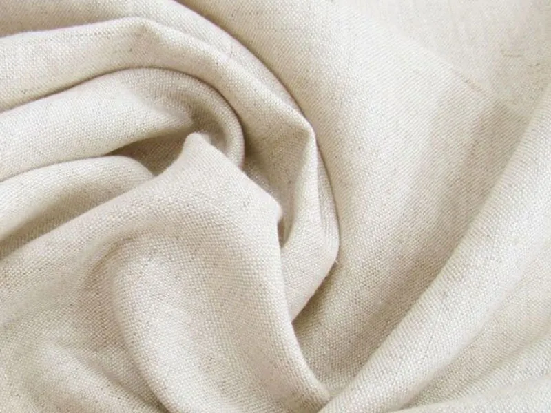 Close-up of soft beige linen fabric with visible texture and folds.