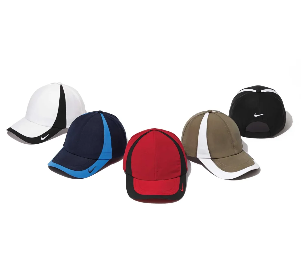 Five baseball caps in white, navy, red, olive, and black with contrasting panels and Nike logo.