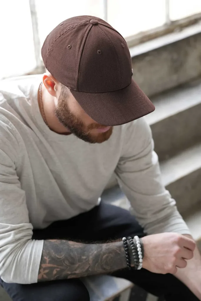 Man wearing brown baseball cap sitting on stairs